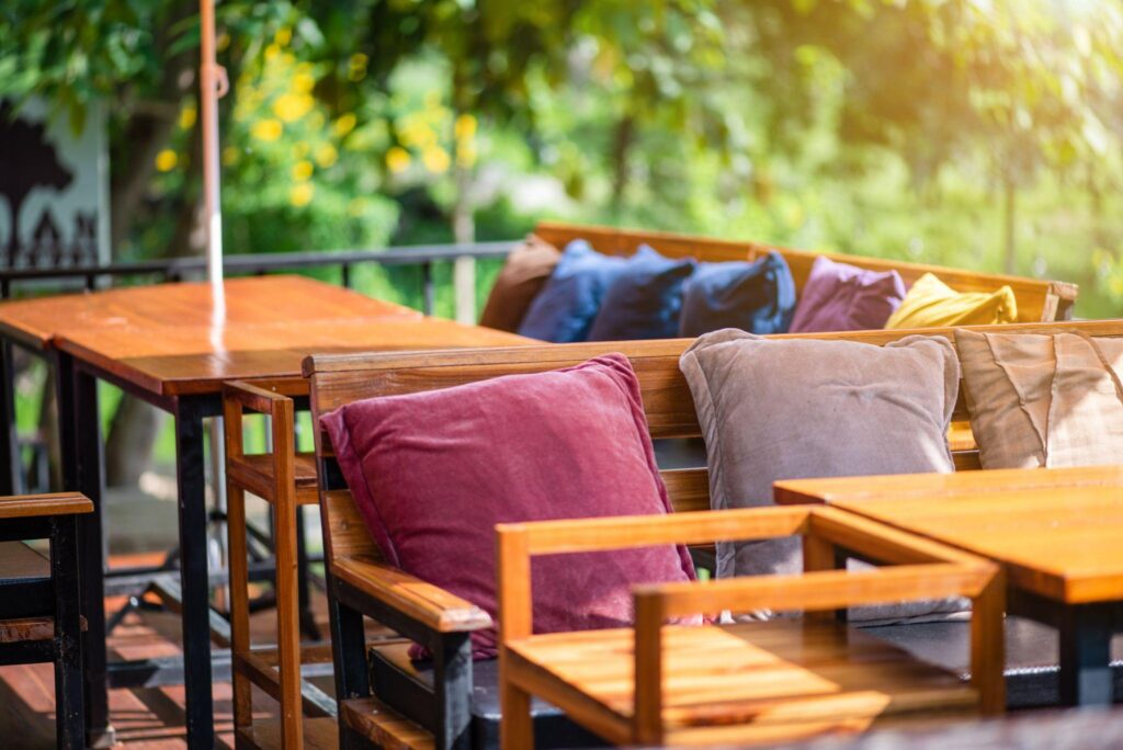 The decoration of the restaurant by using wooden furniture and colored cushions in the midst of nature.